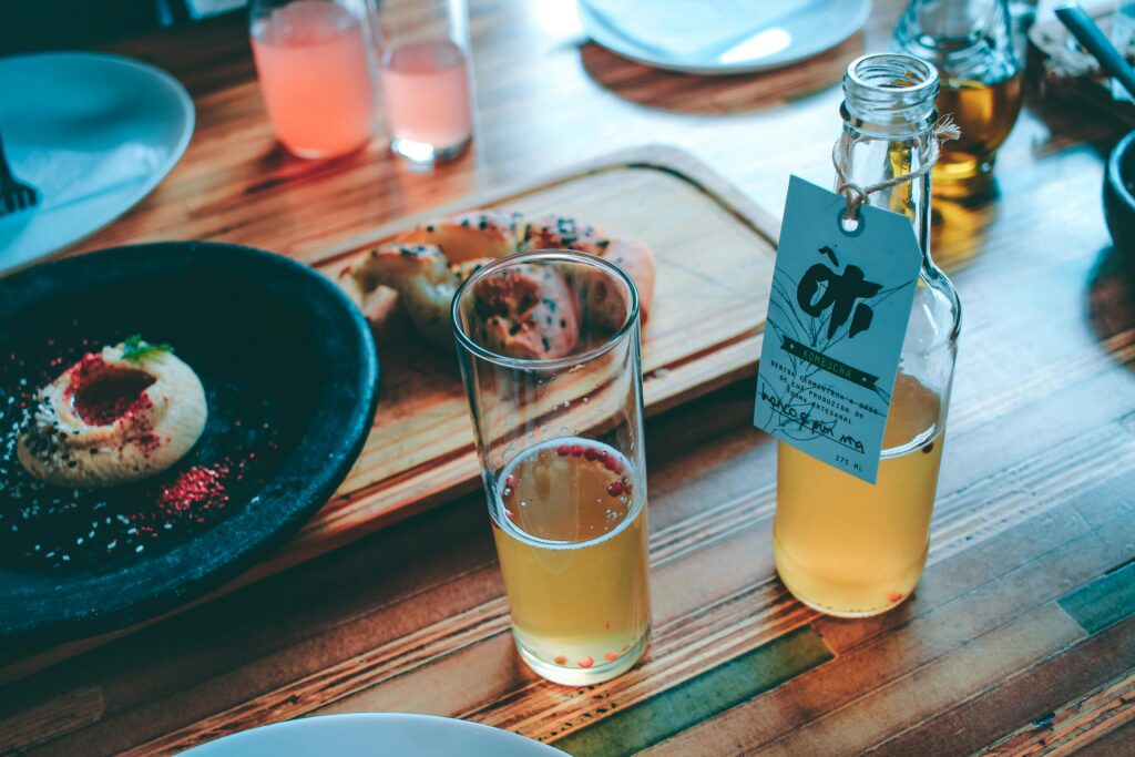 Image of a healthy breakfast alongside a glass and bottle of kombucha.